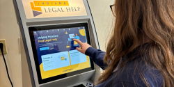 Legal Kiosk A woman with long hair taps a touch screen on the Indiana Legal Help kiosk machine