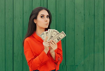 Girl looking thoughtful holding money