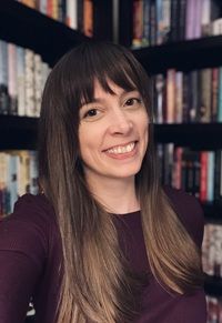 Lindsay Crockett Literary agent Lindsay Crockett in deep purple shirt in front of bookshelf